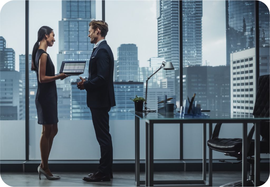A business man and woman standing looking at a laptop